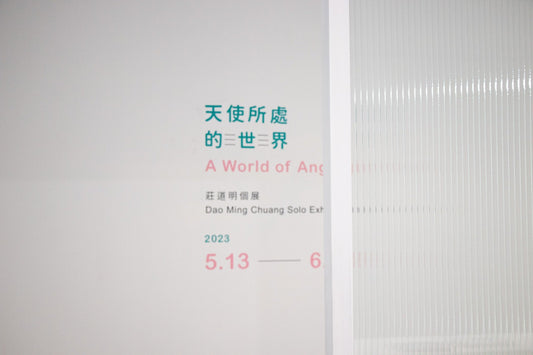 Snippet of Dao Ming Chuang's solo exhibition "A World of Angels" featuring the exhibition title and details in both Chinese and English, displayed on a white wall.