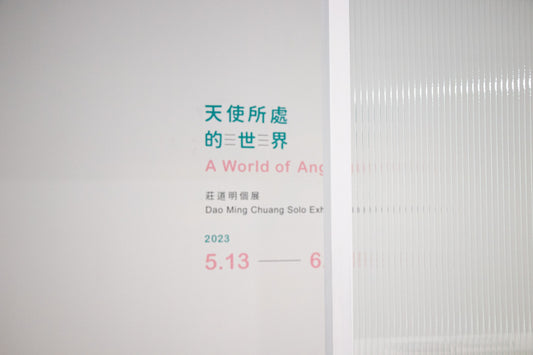 Snippet of Dao Ming Chuang's solo exhibition "A World of Angels" featuring the exhibition title and details in both Chinese and English, displayed on a white wall.